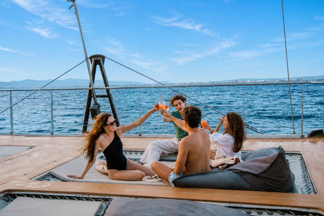 Un grupo brindando en las redes de proa del Saona, con la Bahía de Palma detrás