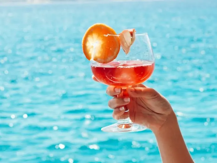 Hand holding a spritz over turquoise water on a private boat trip in Mallorca