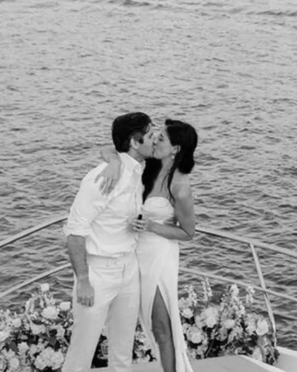 Newlyweds kissing on the bow of a boat decorated with flowers in Mallorca, black and white photo