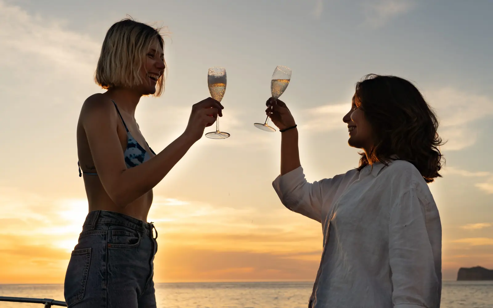 Two friends raising a glass of cava on board a Sa Calma Boats private boat at sunset in Mallorca