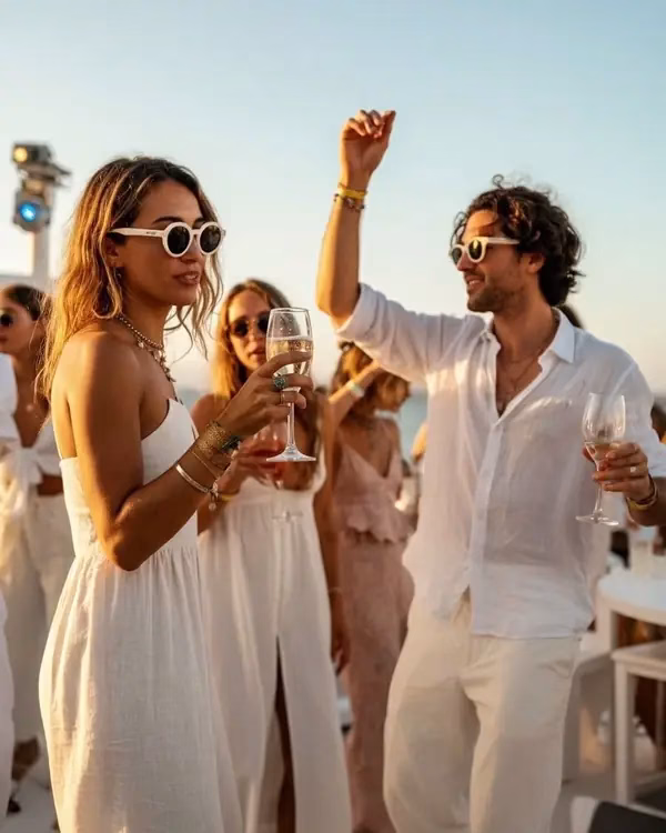 Invitados vestidos de blanco brindando con cava al atardecer durante un evento de incentivos en Mallorca
